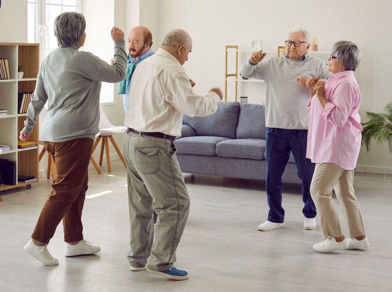Full length portrait of a group of happy smiling senior people men and women having fun and dancing enjoying activities in retirement home together. Leisure time in nursing home concept.